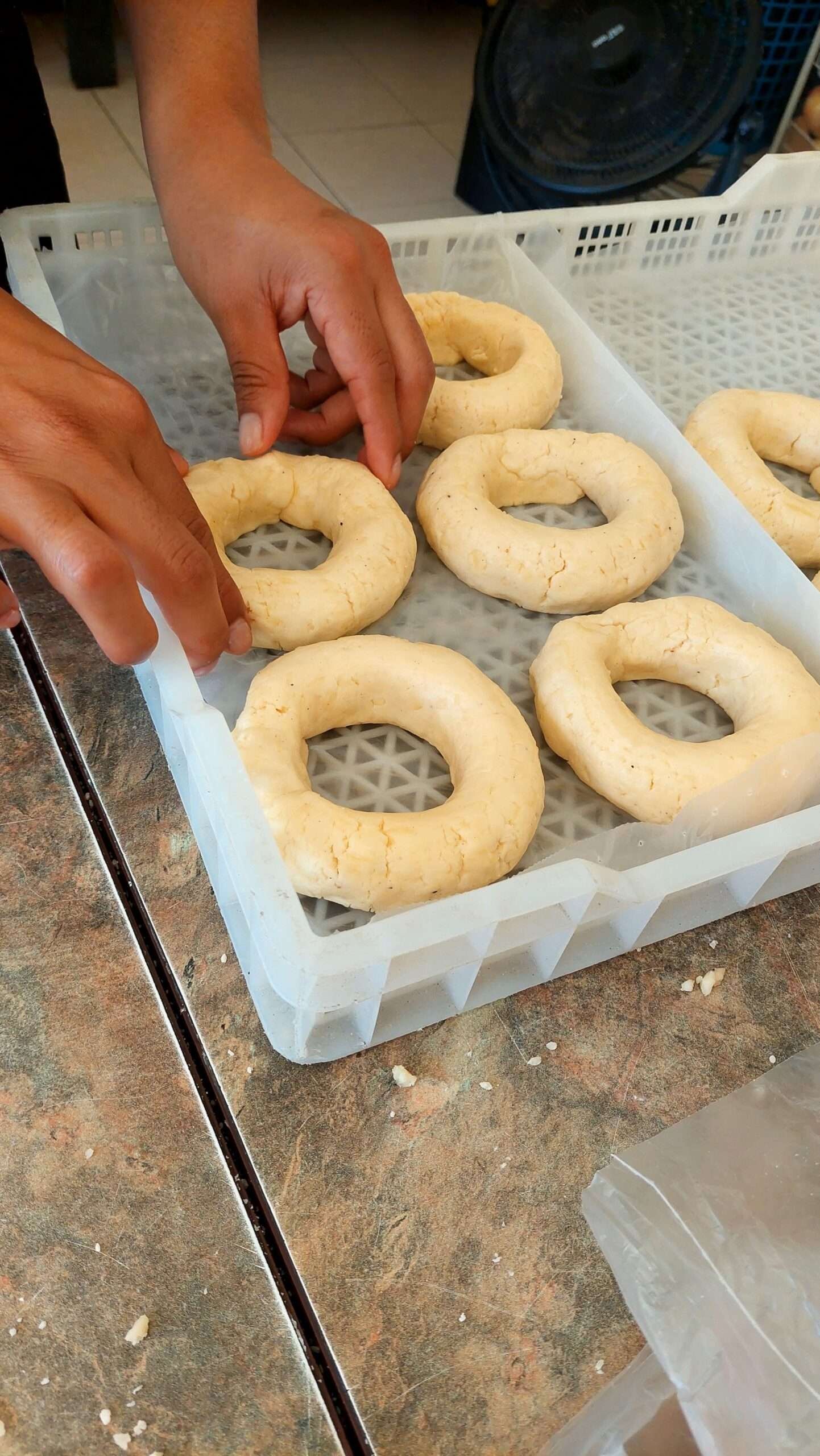 Hands shaping homemade dough doughnuts in a kitchen for baking.